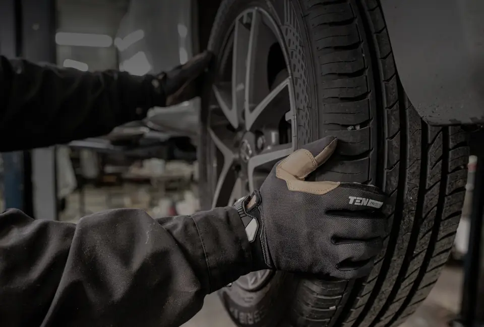 Mechanik v rukavici drží pneumatiku na alu kole